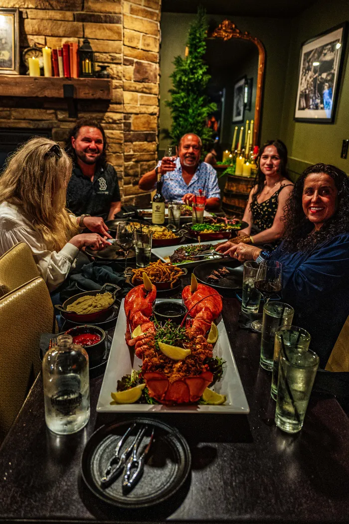 Friends laughing around a table laden with lobster and shared plates