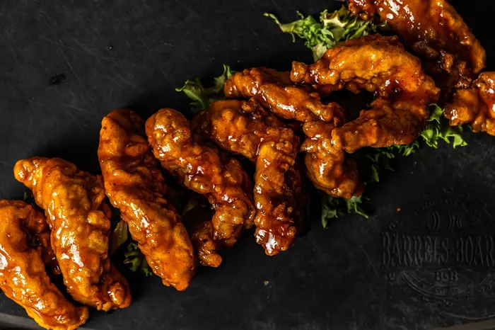 Glazed chicken tenders piled on a slate board