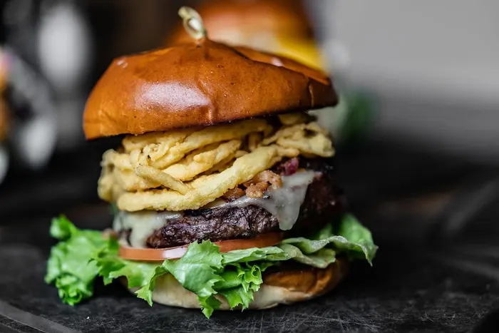A stacked burger topped with crispy onion strings