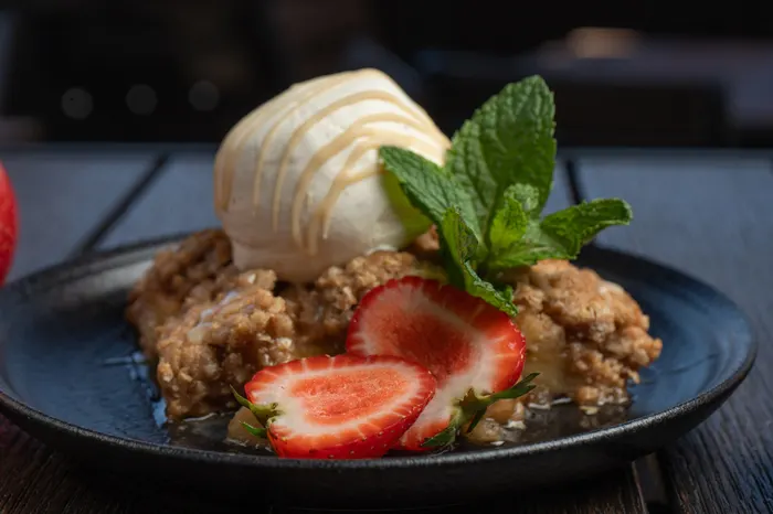 Strawberry crumble dessert with vanilla ice cream and mint